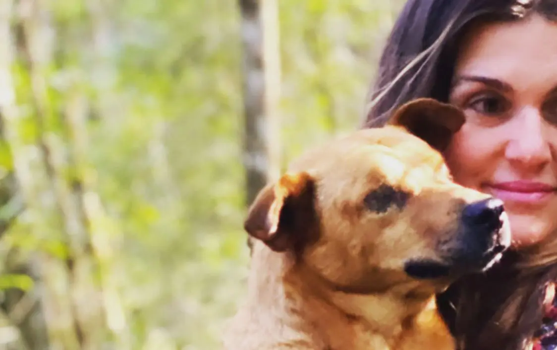 A woman and dog together in a woodland setting